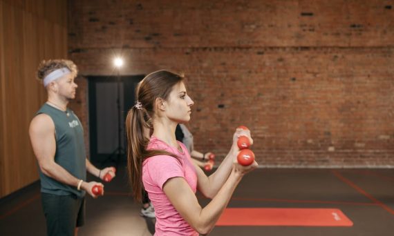 Group of adults exercising indoors with dumbbells, focused on fitness and health.