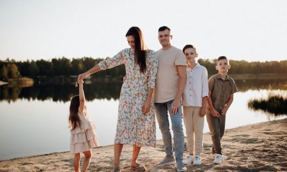 A family of five enjoys a serene lakeside vacation at sunset, capturing precious moments together.